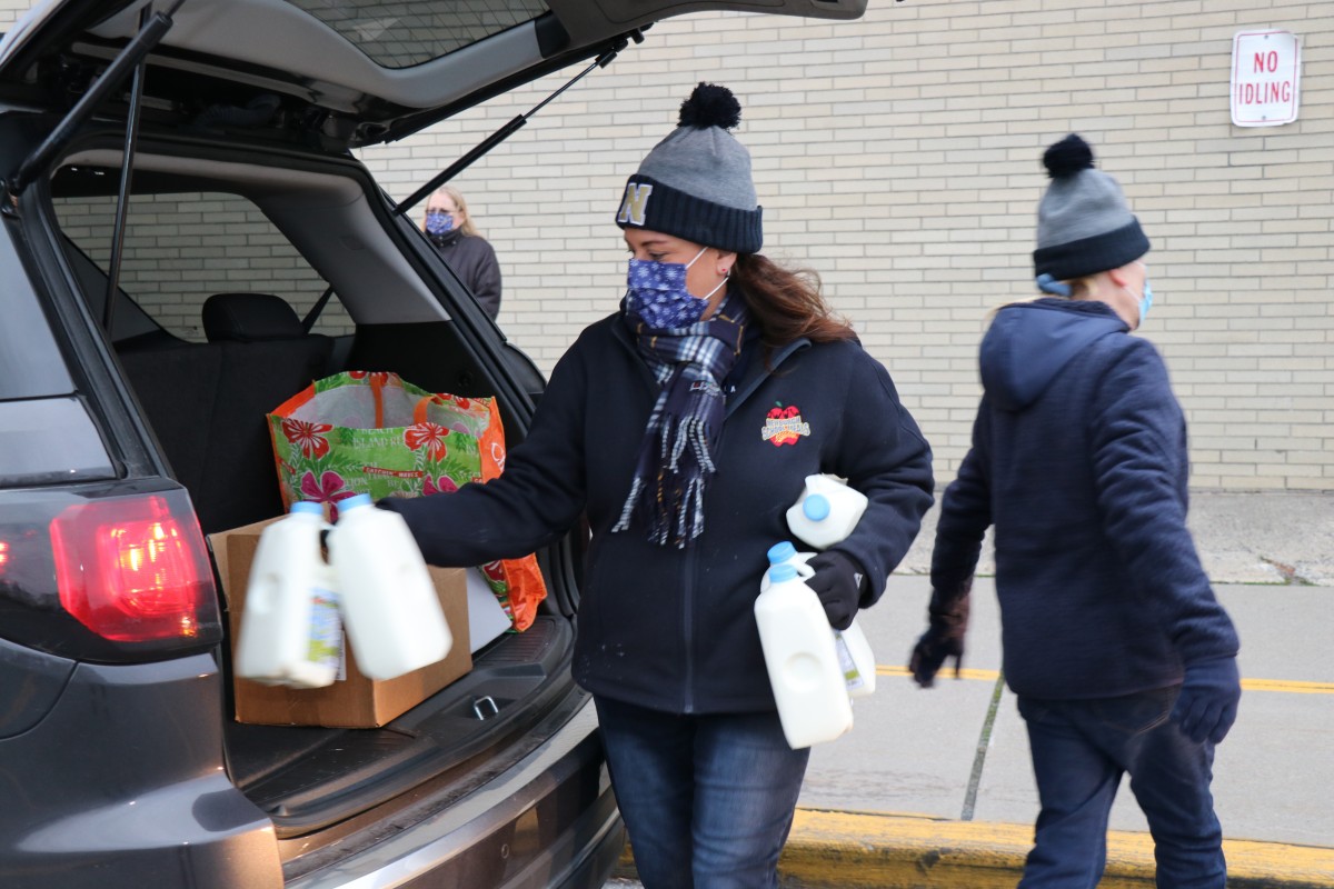 Member of the food services team distributes milk to a car.