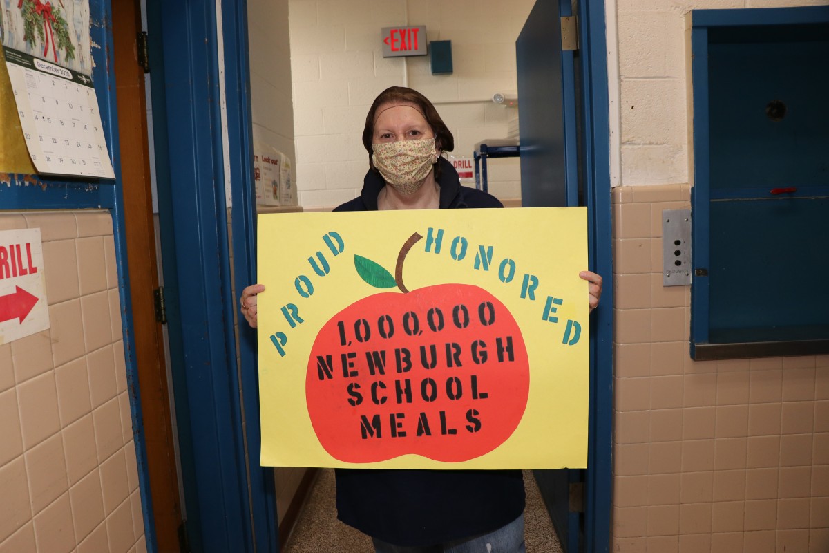 Cafeteria manager holds up celebratory sign.